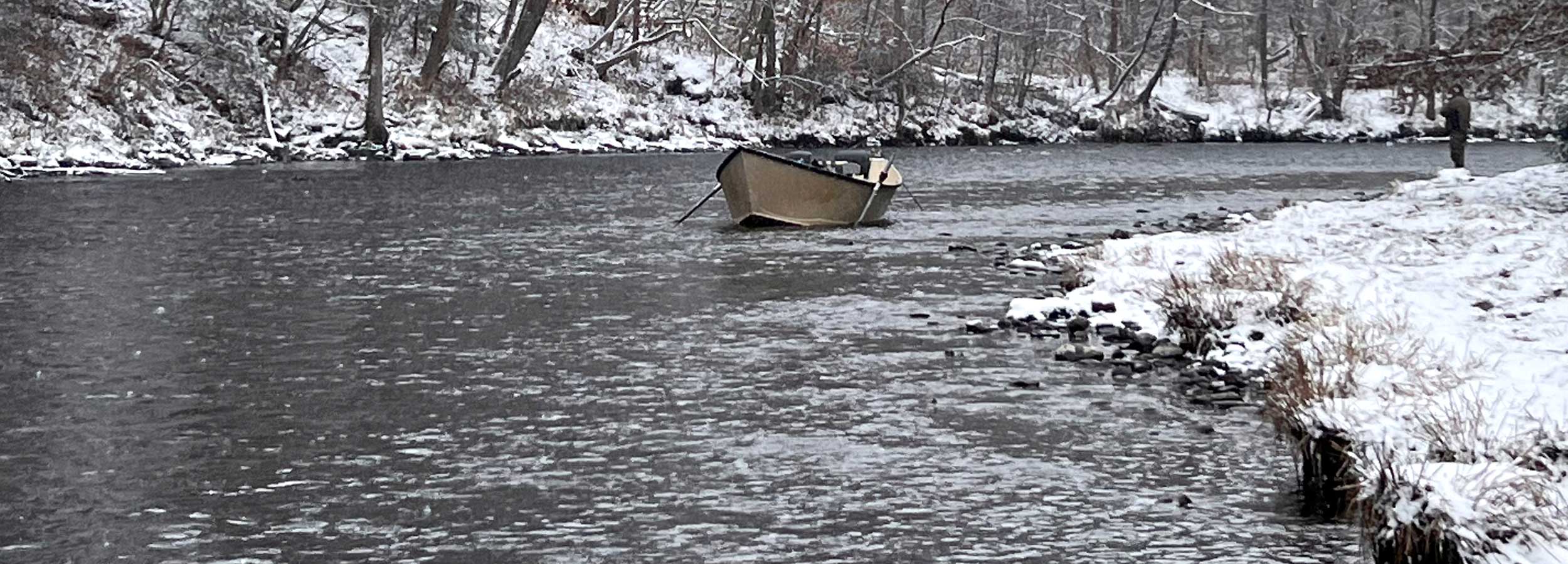photo of Salmon River in the winter with a driftboat in the river and an angler fishing from the snowy shore