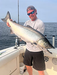 Captain Mark Ledden holding a salmon on board in his lake boat