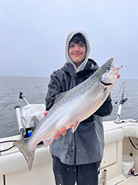 a young fisherman holding a large brown trout caught in Lake Ontario