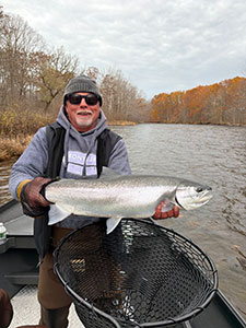 fisherman in Salmon River holding a steelhead in the fall